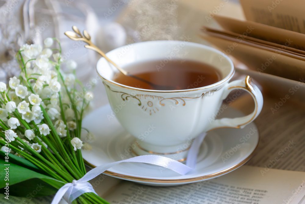 A cup of tea, coffee, a bouquet of lilies of the valley, an old book. A cup of tea, coffee, a bouquet of lilies of the valley, an old book.