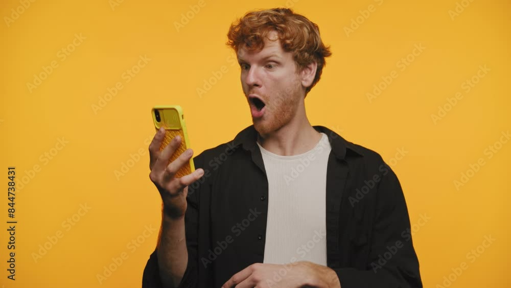 Surprised Man looking at Smartphone on yellow background Surprised Man looking at Smartphone on yellow background
