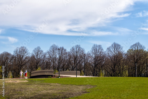 A bridge in a park with human silhouettes and trees in the background