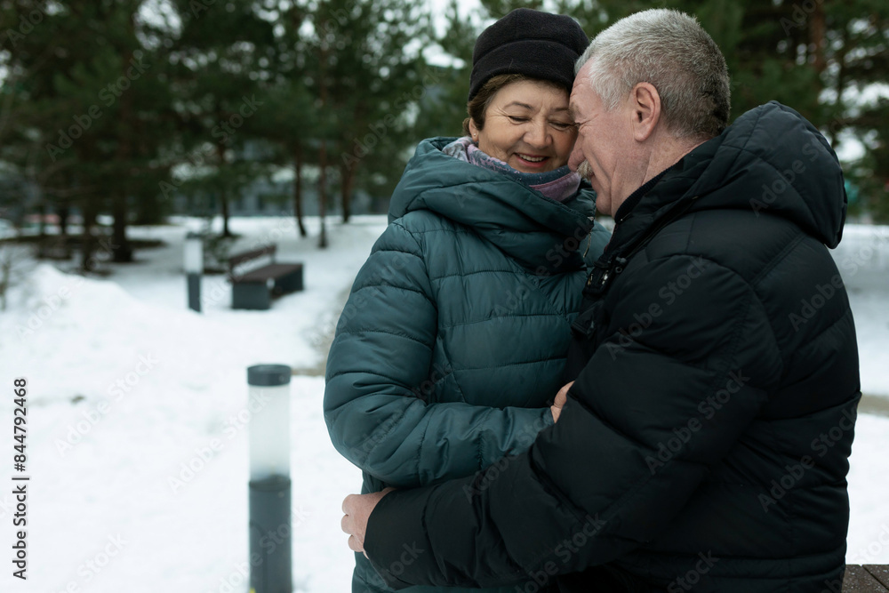 Cute mature couple experiencing love for each other while walking in the park in winter Cute mature couple experiencing love for each other while walking in the park in winter