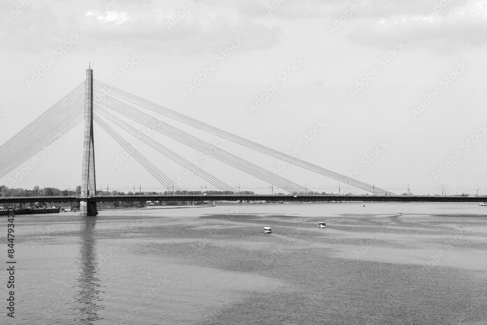 Fototapeta premium Black and white image of a bridge over a river in the morninging