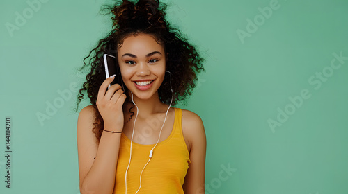 Young woman of African American ethnicity wear yellow tank shirt top talk speak on mobile cell phone conducting pleasant conversation isolated on plain pastel light green background Lifestyle concept. photo