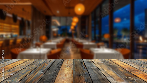 Clear wooden table at forefront, blurred restaurant scene during lively night. The table provides an excellent opportunity for placing food-related products, enhancing night's dynamic restaurant. © Summit Art Creations