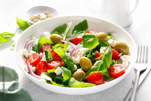 Fresh healthy vegetable Mediterranean salad of feta cheese, tomato, olives, green pepper and green basil leaves