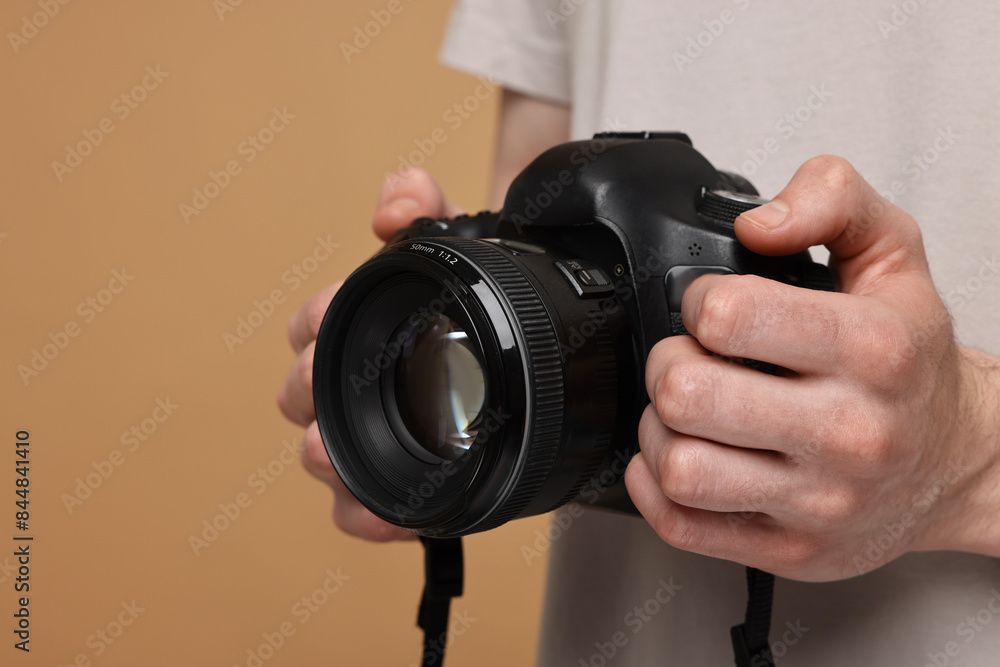Photographer holding camera on beige background, closeup Photographer holding camera on beige background, closeup