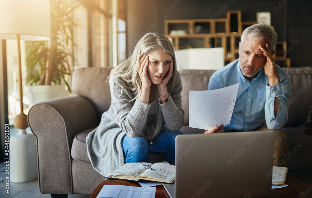 Frustrated couple, reading and documents with laptop in financial crisis, mistake or debt on sofa at home. Man and woman with paperwork in finance, rent or budget for bills, expenses or mortgage Frustrated couple, reading and documents with laptop in financial crisis, mistake or debt on sofa at home. Man and woman with paperwork in finance, rent or budget for bills, expenses or mortgage