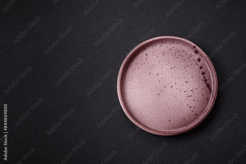 Empty ceramic round plate on dark textured concrete background Empty ceramic round plate on dark textured concrete background