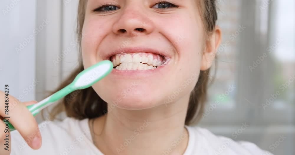 A teenage girl brushes her teeth in the early morning. A teenage girl brushes her teeth in the early morning.