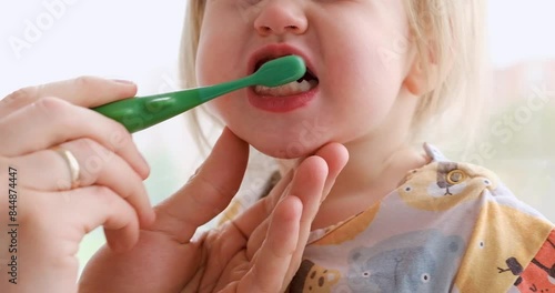 Parents brush the teeth of a little child toddler.