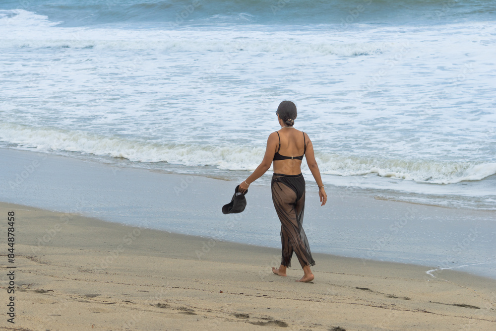 Solitary latin woman Walking Away on a Quiet Beach Solitary latin woman Walking Away on a Quiet Beach