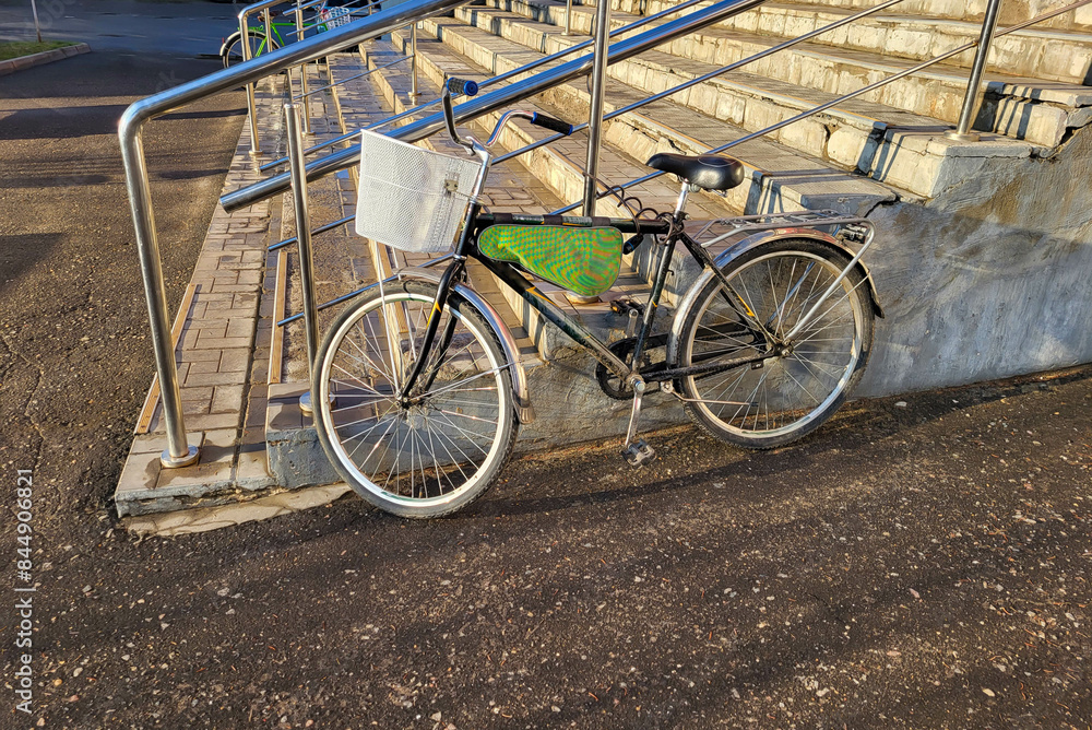 Obraz premium A bicycle with a basket stands near the porch with a railing.