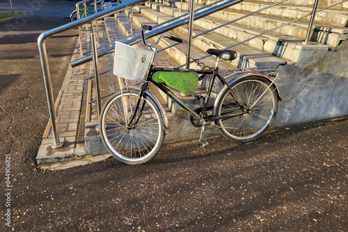 A bicycle with a basket stands near the porch with a railing.