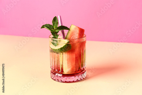 Glass of fresh watermelon lemonade with lime and mint on yellow table