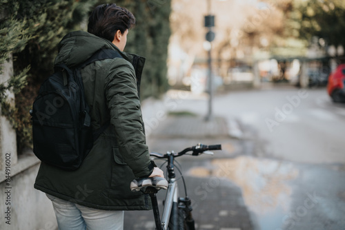 Wallpaper Mural A rear view of an individual with a backpack standing next to a bicycle on a city street, ready for a ride. Torontodigital.ca