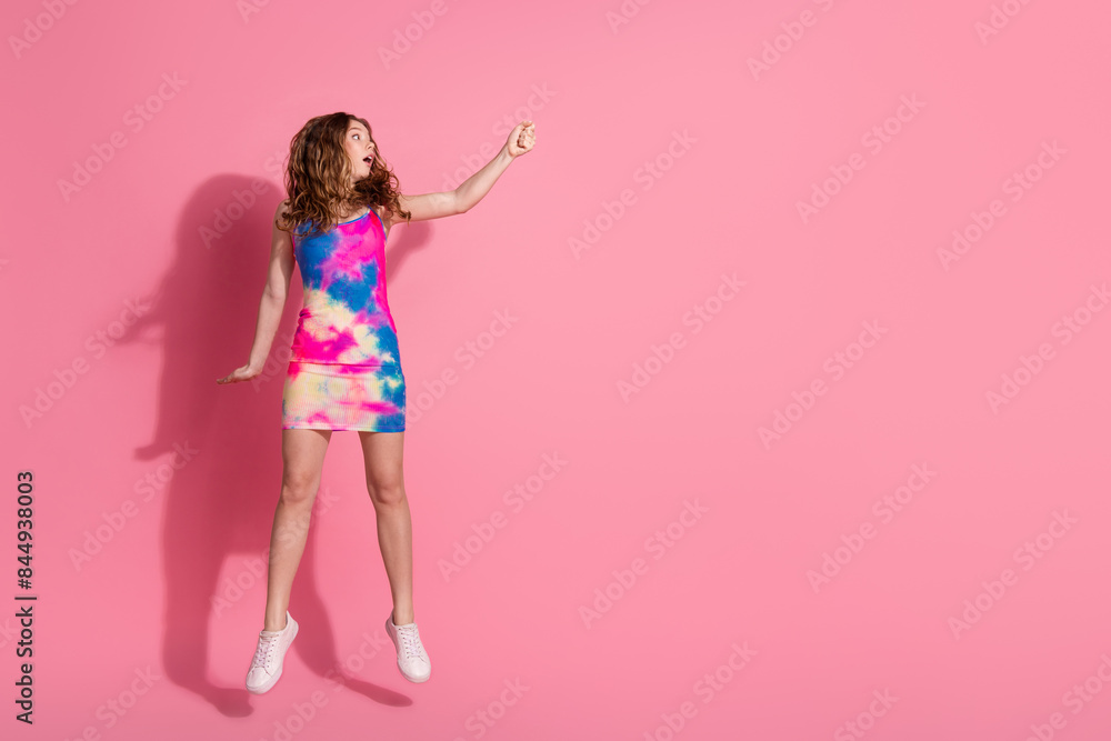 Full length photo of adorable lovely girl wear retro outfit jumping rising fist empty space isolated pink color background Full length photo of adorable lovely girl wear retro outfit jumping rising fist empty space isolated pink color background