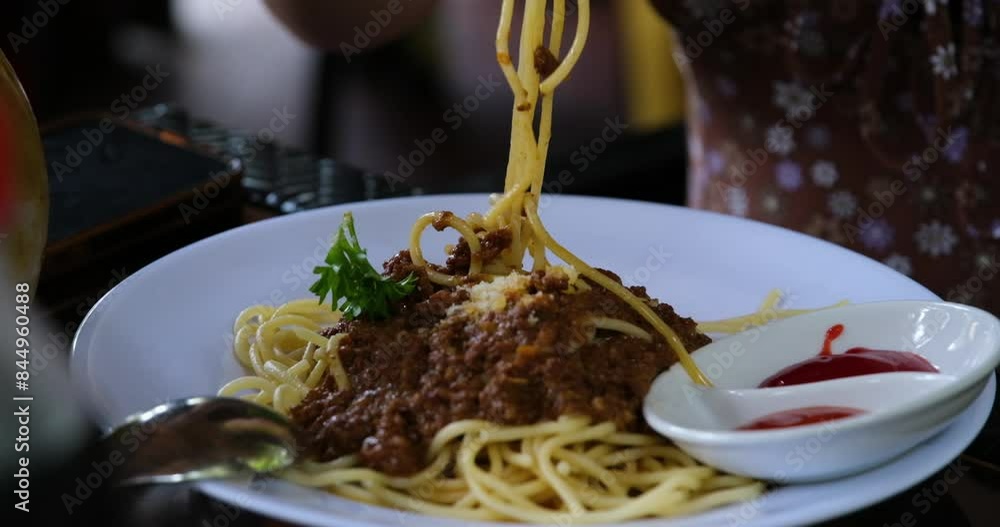 Slow close-up panning shot of spaghetti mixed with meat and tomato sauce