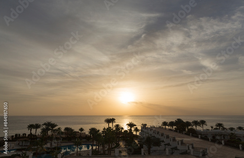 Sunrise on the sea coast. The movement of the sun and clouds across the sky. Park recreation areas of Egypt. Garden and landscape design.