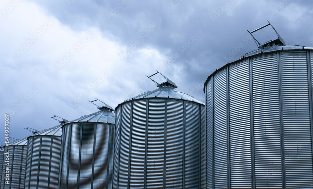 Minimal view to a row of gray metal granaries and sky. Minimal view to a row of gray metal granaries and sky.