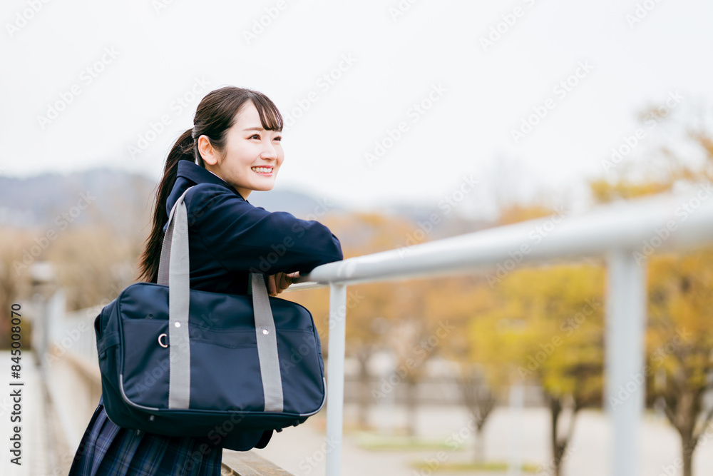 Obraz premium 下校・通学・登校中に待ち合わせ・景色を眺める制服姿の女子高校生・女子高生・女子中学生 