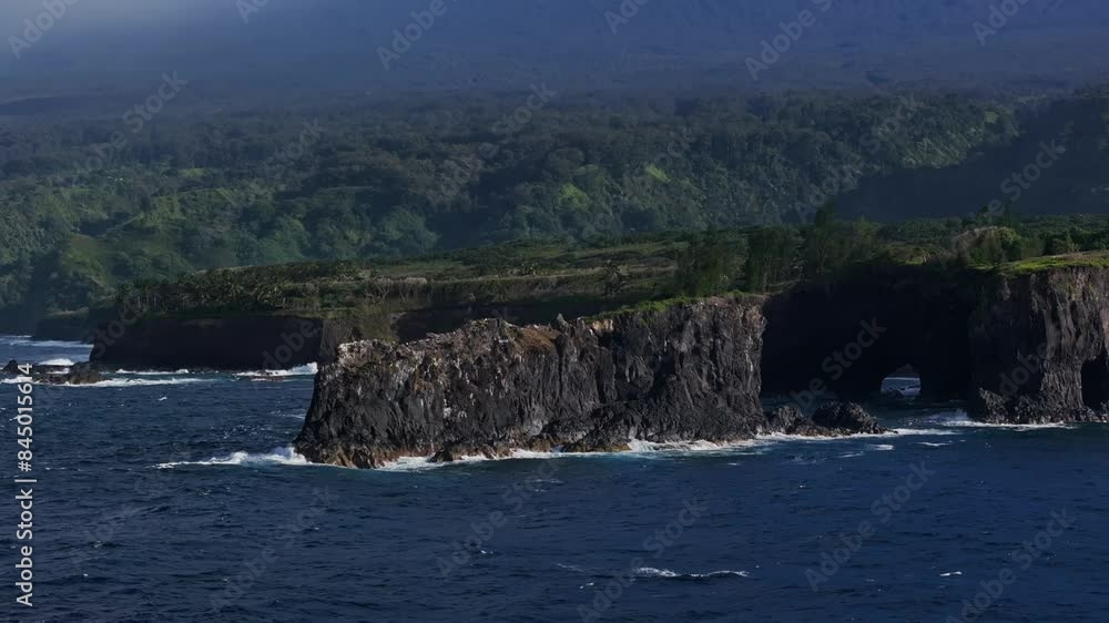 Wide aerial orbiting view of black rock formation jutting out into the ocean off the coast of Maui's north shore Wide aerial orbiting view of black rock formation jutting out into the ocean off the coast of Maui's north shore