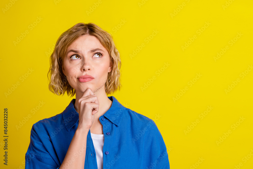 Portrait of pretty young lady look interested empty space wear blue shirt isolated on yellow color background Portrait of pretty young lady look interested empty space wear blue shirt isolated on yellow color background