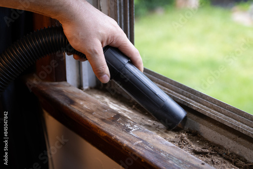 Cleaning debris out of window ledge and grooves with vacuum.