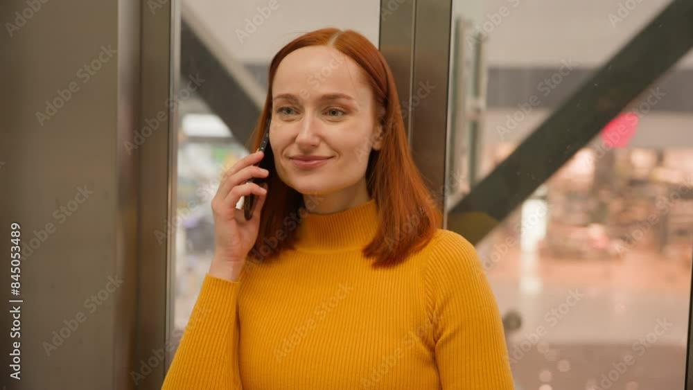 Portrait smiling successful Caucasian red haired girl woman client businesswoman female talk answer speaking mobile cell phone device call moving down indoors glass modern elevator shopping mall store