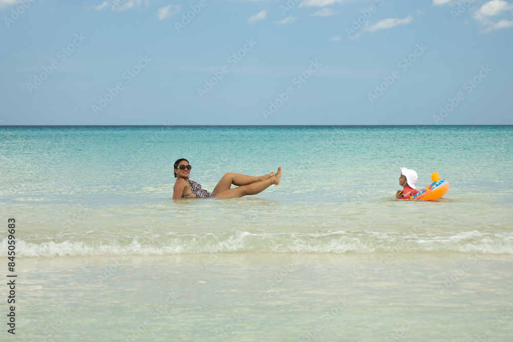 Obraz premium happy mother and her 2-year-old daughter enjoying the caribbean sea