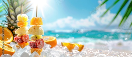 Fresh fruit skewers with pineapple, oranges, and ice on a sunny beach with room for text photo