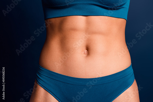 No filter cropped photo of slim lady belly lingerie accepting imperfect skin isolated blue color background