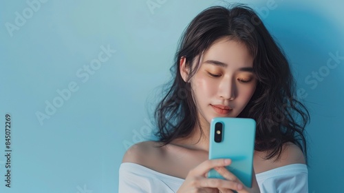 Beautiful asian women using phone and similing on blue background. copy space for text.