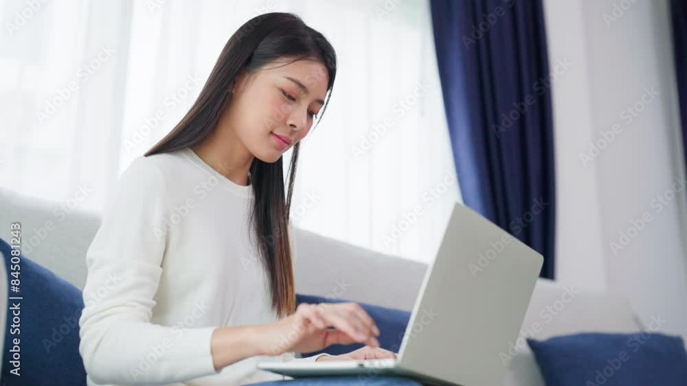 Young asian woman using laptop while seated on couch at home Young asian woman using laptop while seated on couch at home