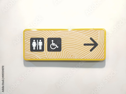 Wallpaper Mural A signage points to the public toilet and includes a symbol for disable person. Clear icons of a man, woman, and wheelchair on yellow design background with a black arrow indicating the direction. Torontodigital.ca
