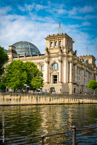 Teilansicht des Reichstagsgebäudes, im Vordergrund die Spree, leicht bewölkter blauer Himmel, vertikal