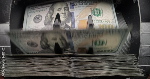 Stack of hundred dollar bills in counting machine, slow motion. Rotating blades carefully turn over and count each banknote, copy space. Sorting and counting American currency for financial purposes.