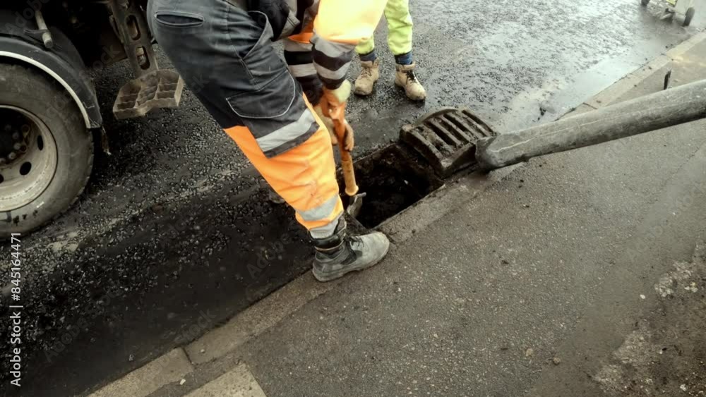 Workers clear drain in city street Workers clear drain in city street