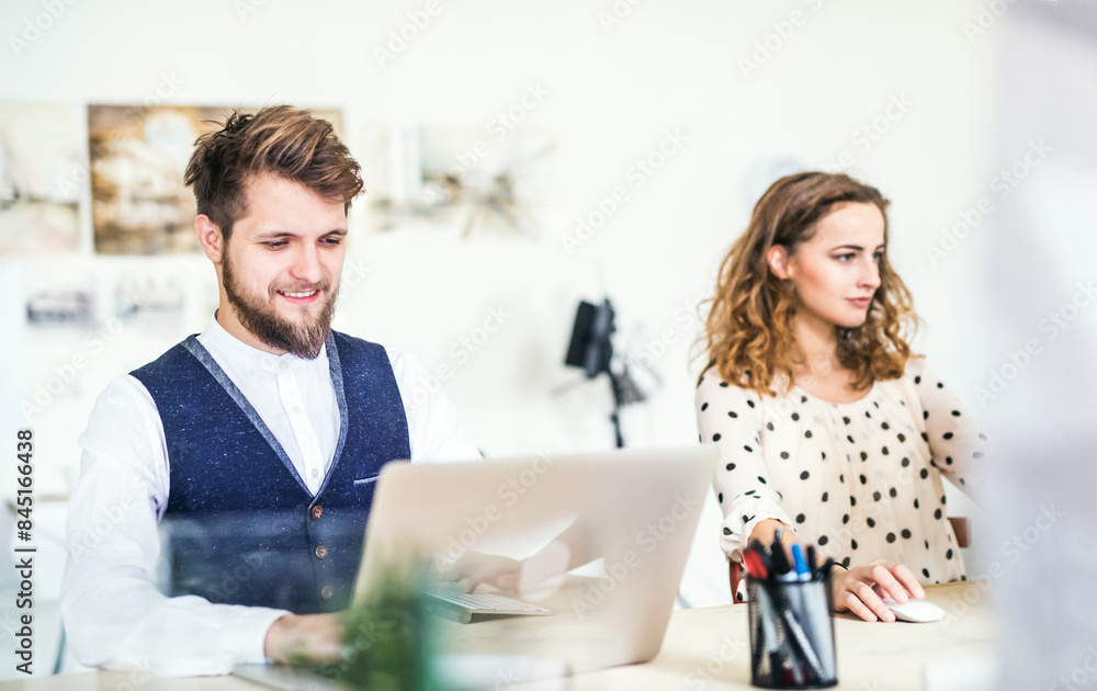 Two colleagues working on a new project together in a startup company office. Working in co-working space. Two colleagues working on a new project together in a startup company office. Working in co-working space.