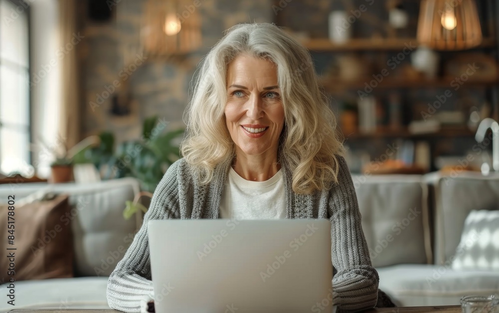 A woman is sitting in front of a laptop computer with a smile on her face. She is happy and content while using the laptop A woman is sitting in front of a laptop computer with a smile on her face. She is happy and content while using the laptop