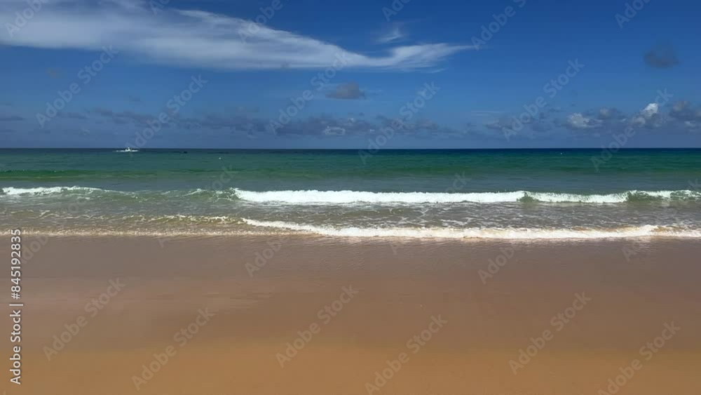 A beautiful tropical beach with waves lapping the shore. Turquoise ocean on a sunny summers day. Summer holidays and paradise beach concept. Karon Beach, Phuket, Thailand. A beautiful tropical beach with waves lapping the shore. Turquoise ocean on a sunny summers day. Summer holidays and paradise beach concept. Karon Beach, Phuket, Thailand.