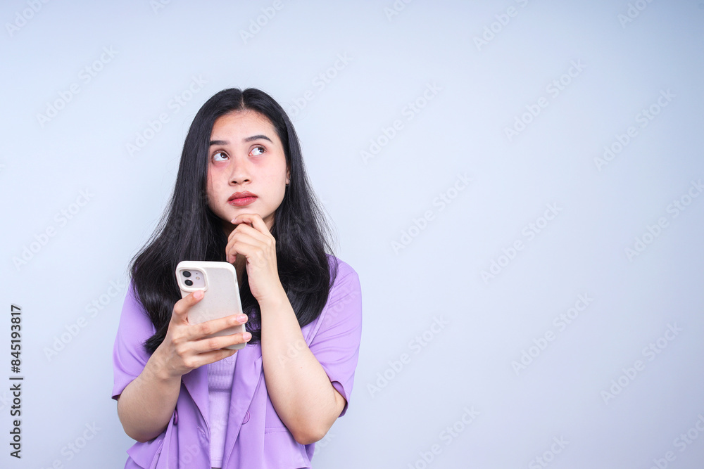 Asian businesswoman using mobile phone and looking away isolated over white background Asian businesswoman using mobile phone and looking away isolated over white background