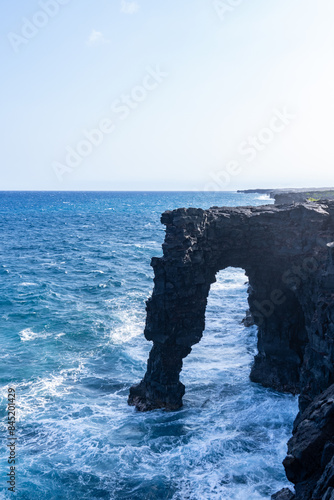 Hōlei Sea Arch is a 90-foot (27-meter)-high natural arch located in Hawaii, on the southern coast of the Big Island, south of Kīlauea. natural bridge of lava cliffs. photo