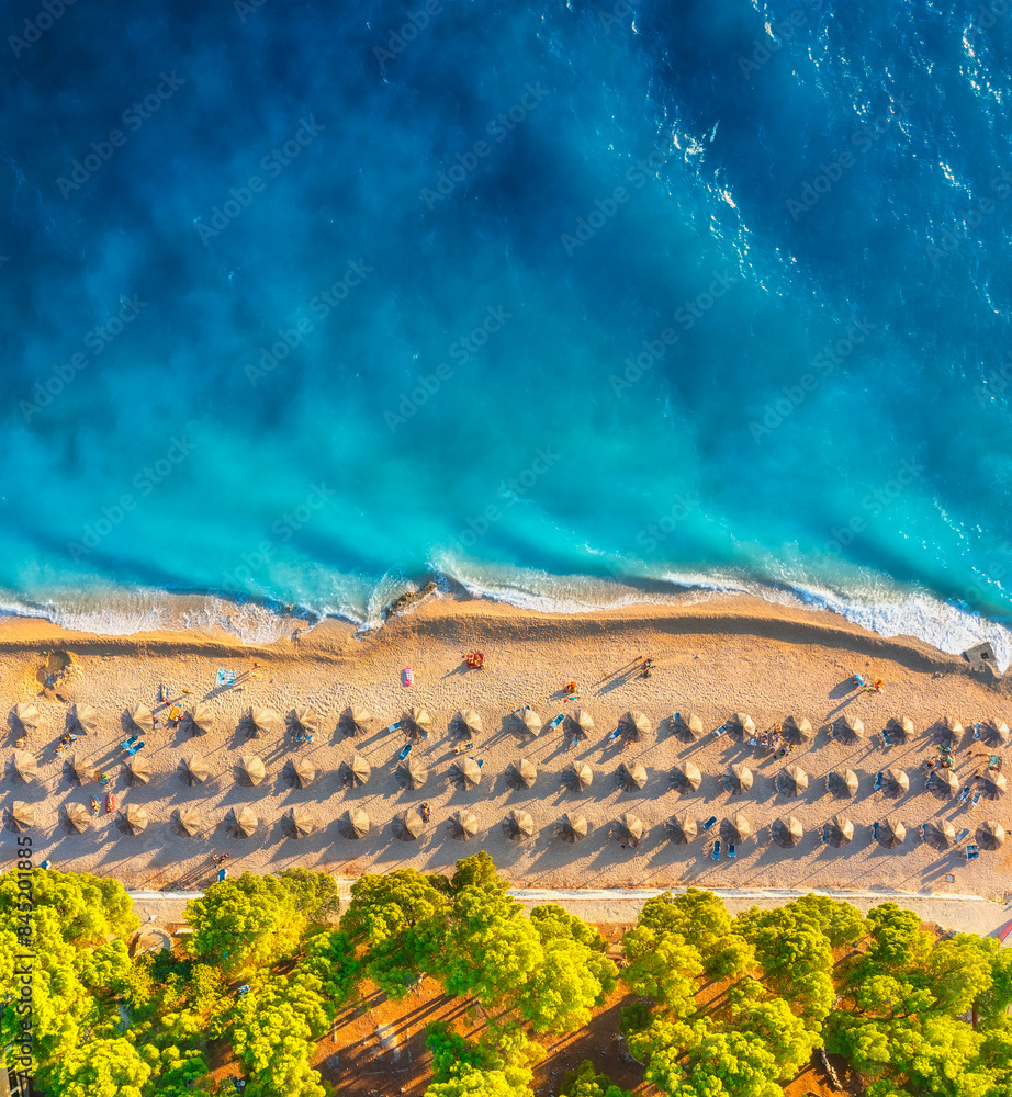 Aerial view on the beach and umbrellas. Vacation and adventure. Beach and blue water. Top view from drone at beach and azure sea. View on the coast from drone.