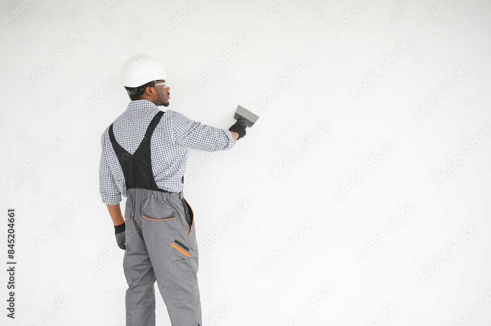 African american Plasterer in working uniform plastering the wall indoors