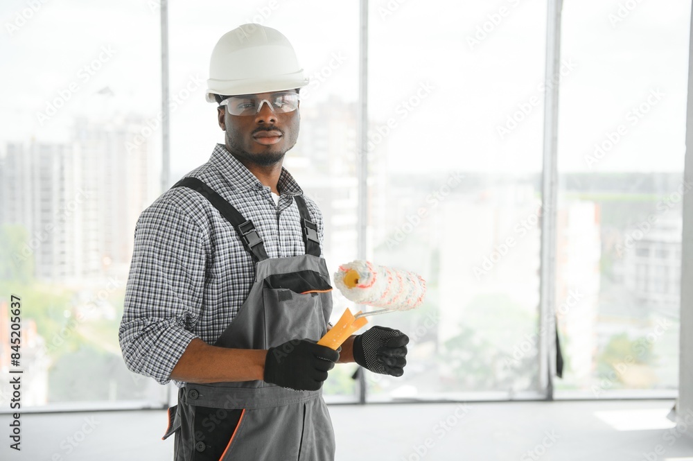 Portrait of handsome young african american male builder in hard hat, working at construction site Portrait of handsome young african american male builder in hard hat, working at construction site
