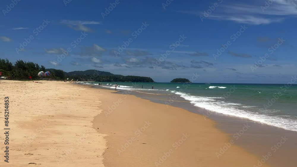 Tourists on a tropical beach with turquoise seas. Turquoise ocean on a summer day. Summer holidays and paradise beach concept. Karon Beach, Phuket, Thailand. Tourists on a tropical beach with turquoise seas. Turquoise ocean on a summer day. Summer holidays and paradise beach concept. Karon Beach, Phuket, Thailand.