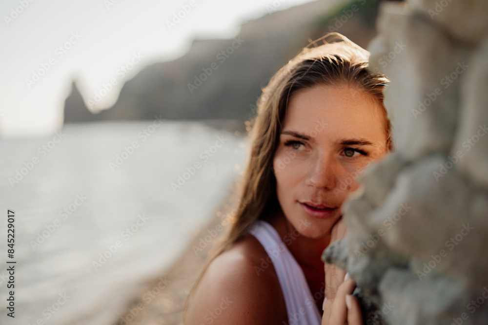 A woman with long hair is standing on a beach, looking at the water A woman with long hair is standing on a beach, looking at the water