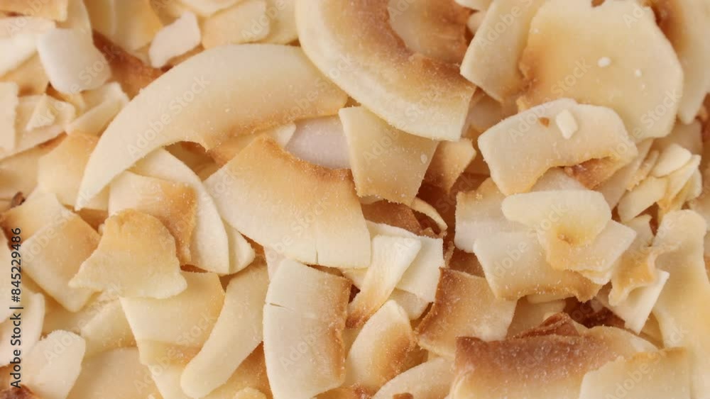 Thin sweet toasted coconut chips circle rotation close up top view Thin sweet toasted coconut chips circle rotation close up top view