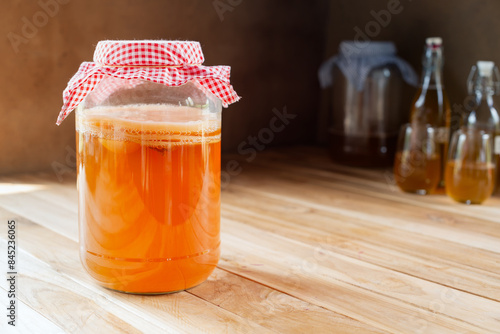 homemade fermented drink Kombucha in a glass jar on wooden table. photo