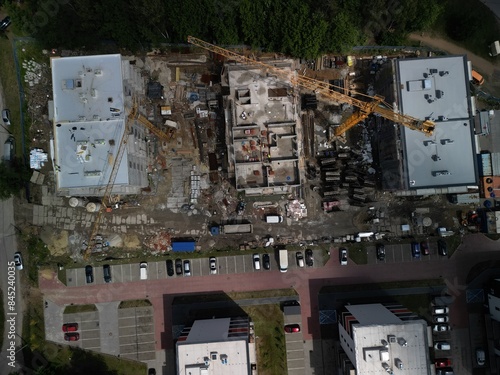 Tilted Aerial View of Residential Construction Site with Two Working Cranes A tilted aerial view captures the construction of three residential blocks with two active cranes on the site. The perspecti photo