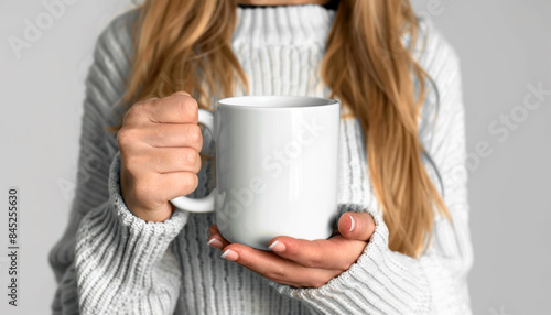 blonde woman in a white winter sweater holding a white cup
